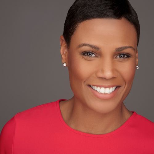 Professional headshot of a Tanya Baskin smiling businesswoman in a bright red blouse against a gray background, representing leadership, branding, strategic communications, and executive consulting.